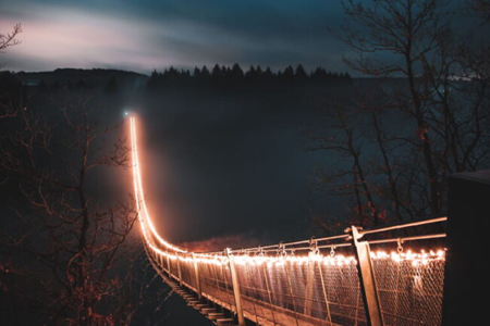 beleuchtete haengeseilbrücke im dunkeln